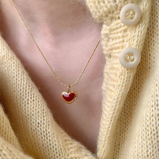 Colar dourado com pingente de coração vermelho